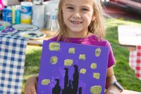 Art in the Park 2021 young girl smiling holding up her starry night like painting